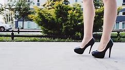 Sexy woman legs in black high heels shoes walking in the city urban street. Steadicam stabilized shot, Slow motion. Female legs in high-heeled shoes in the morning. Cinematic shot.