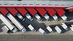 Aerial top view of an industrial warehouse loading dock, where many delivery vans and trucks.