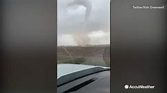 Large tornado towers over driver passing by