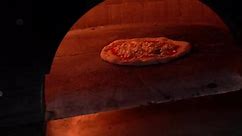 Pizza baking in an Italian pizza oven with fire around it in slow motion