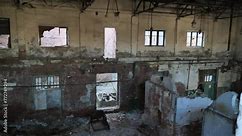 An abandoned and crumbling industrial building. Brick ovens can be seen. Perhaps the building served as a boiler room. Dangling light bulbs and metal pipes add to the eerie atmosphere