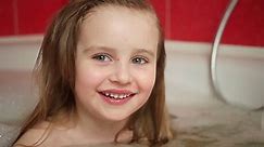 Cute toddler girl taking bath with foam and smilling. Child girl playing in the bathroom