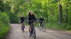 Красивые молодые женщины катаются на велосипедах в живописном лесу в летний день Здоровый образ жизни