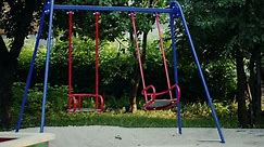 Empty swing set moving on its own in a playground - Free Stock Video