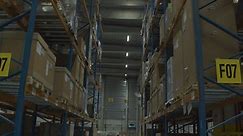 Premium stock video - Tilt up of aisle between high racks in industrial warehouse