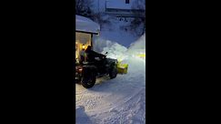 Man uses ATV with a massive snow blodet in the front to remove the snow