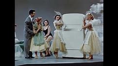 1950s: Man and women dance around refrigerator. Women dance down ramp near appliances. Women ballet dance.