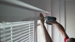 Professional worker man using screw to install the blinds on a pvc window in a house