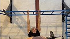 Person is hanging from a bar and using weights to stretch her legs back!