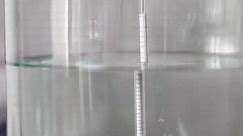 alcohol distilling process closeup - liquid distilled transparent liquid flowing in large glass jar