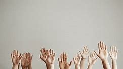 Many male and female hands of different colors and sizes on a white background are raised forward with their palms up. Forest of hands. Volunteers
