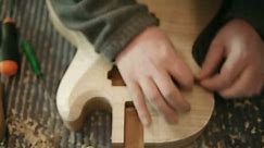 Hands of young man at work as craftsman in italian workshop with guitars and musical instruments. Dolly shot