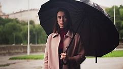 Young Serious Woman Standing Under Umbrella in Rain, Sad Weather in City